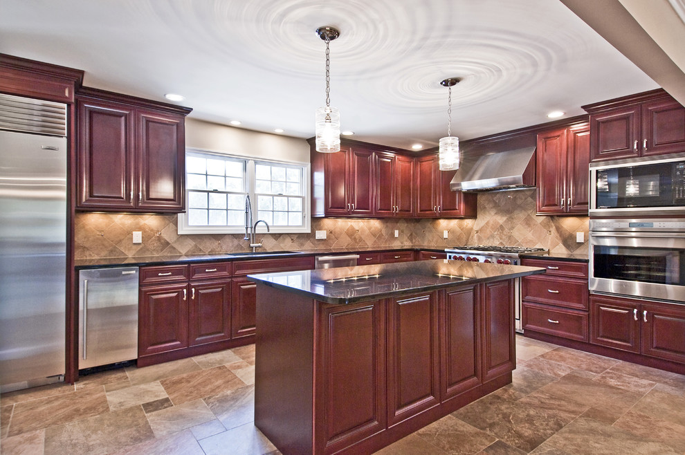Inspiration for a large transitional l-shaped ceramic tile kitchen remodel in New York with an undermount sink, raised-panel cabinets, medium tone wood cabinets, beige backsplash, stone tile backsplash, stainless steel appliances and an island