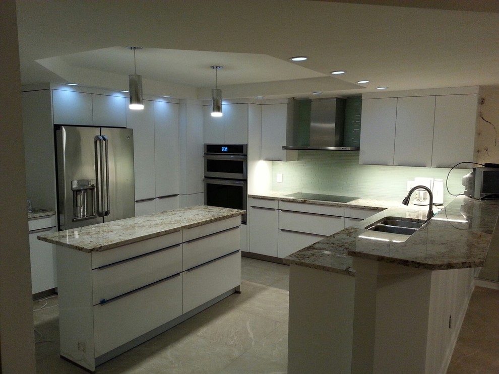 Photo of a medium sized contemporary u-shaped kitchen pantry in Tampa with a double-bowl sink, flat-panel cabinets, white cabinets, granite worktops, green splashback, glass tiled splashback, stainless steel appliances, ceramic flooring, an island and beige floors.