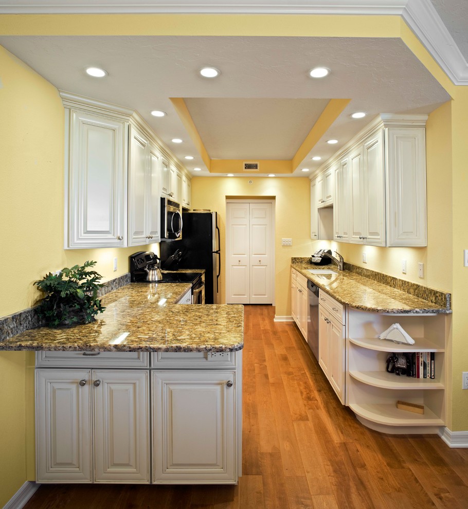 This is an example of a small traditional galley open plan kitchen in Tampa with a submerged sink, raised-panel cabinets, white cabinets, granite worktops, multi-coloured splashback, stone slab splashback, stainless steel appliances, medium hardwood flooring and a breakfast bar.