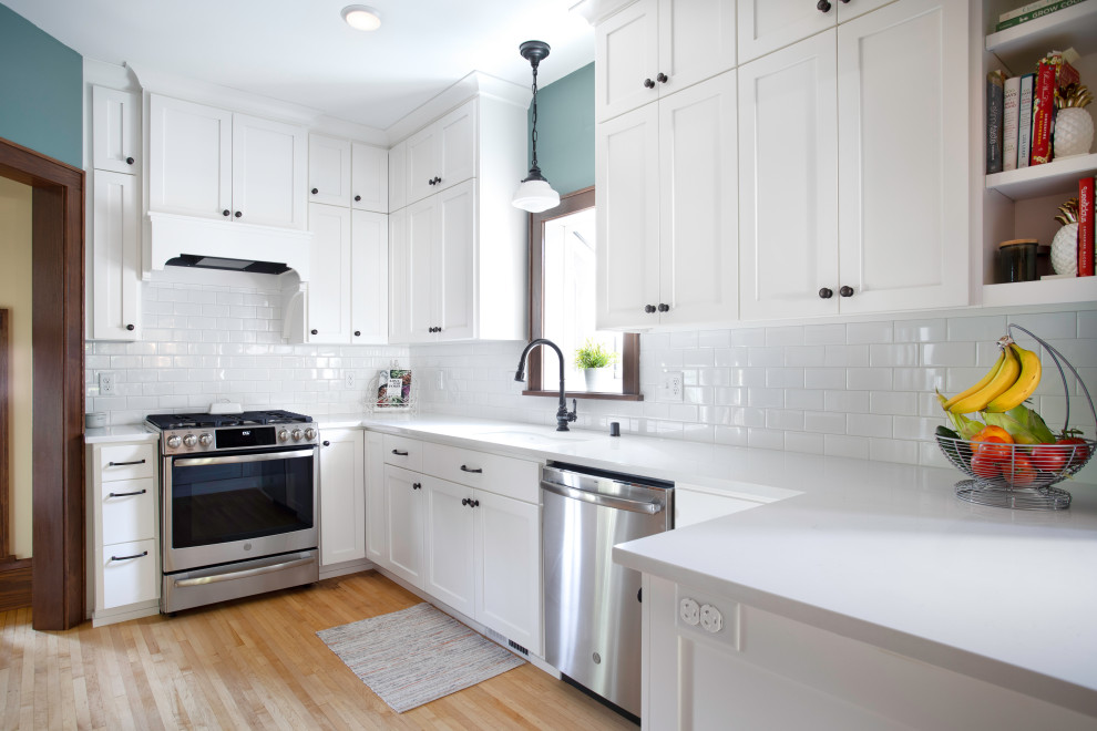 Klassische Küche mit Unterbauwaschbecken, Schrankfronten im Shaker-Stil, weißen Schränken, Quarzwerkstein-Arbeitsplatte, Rückwand aus Metrofliesen, hellem Holzboden und weißer Arbeitsplatte in Minneapolis