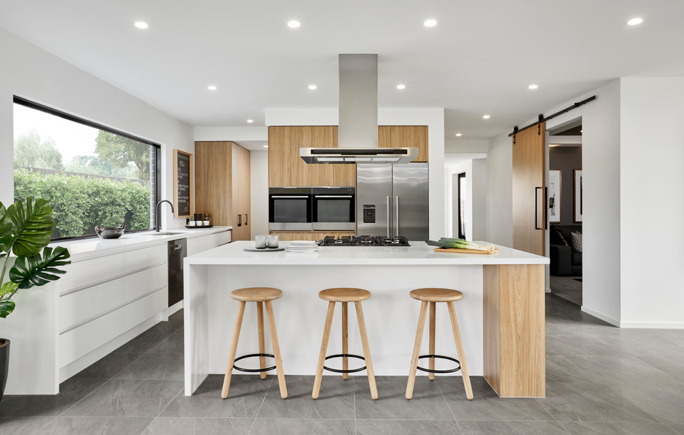 Photo of a scandi l-shaped kitchen in Other with a submerged sink, flat-panel cabinets, light wood cabinets, stainless steel appliances, an island, grey floors and white worktops.