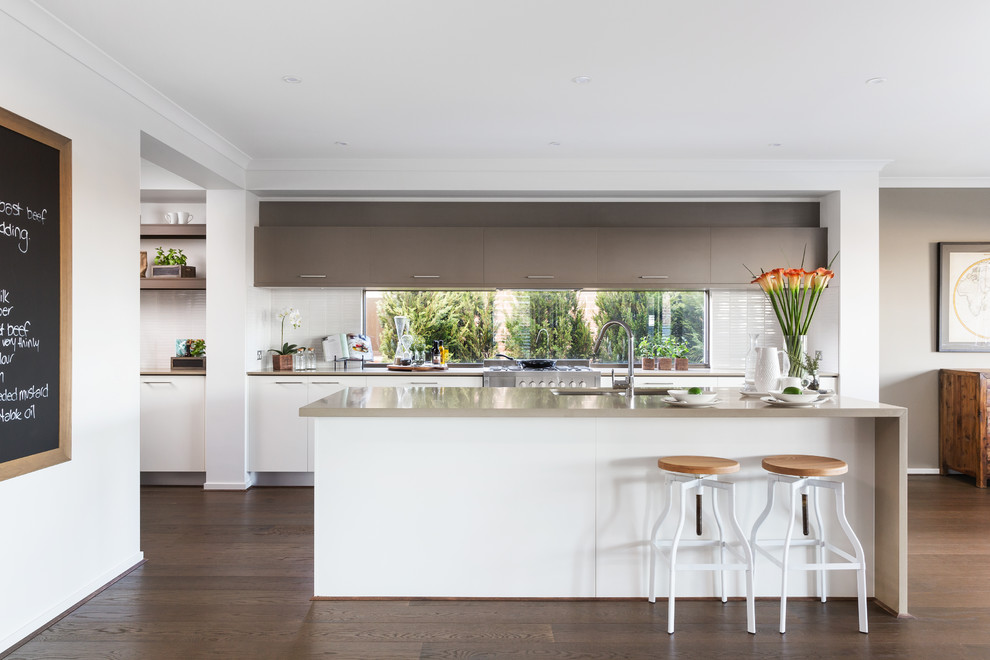 Imagen de cocinas en L contemporánea con fregadero bajoencimera, armarios con paneles lisos, puertas de armario blancas, salpicadero blanco, suelo de madera oscura y una isla