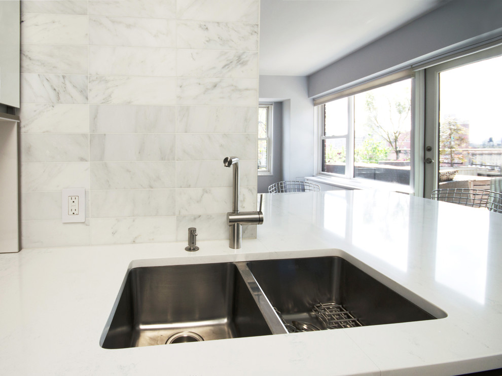 Example of a mid-sized trendy galley porcelain tile open concept kitchen design in New York with a double-bowl sink, flat-panel cabinets, white cabinets, quartzite countertops, white backsplash, stainless steel appliances, a peninsula and stone tile backsplash