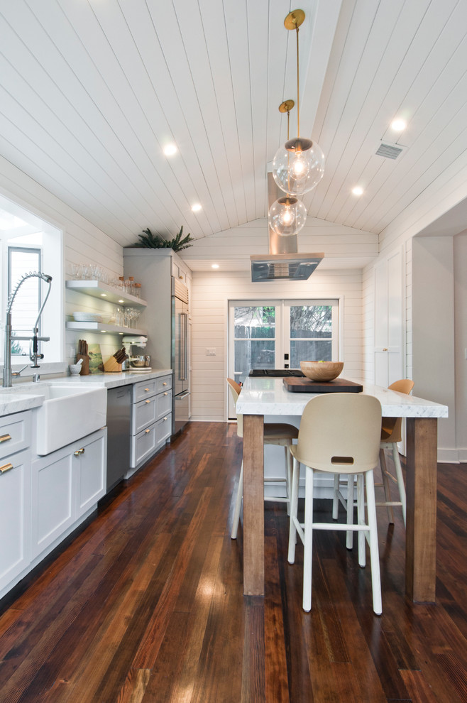 Inspiration for a medium sized farmhouse galley kitchen/diner in Los Angeles with a belfast sink, shaker cabinets, white cabinets, marble worktops, white splashback, wood splashback, stainless steel appliances, painted wood flooring and an island.