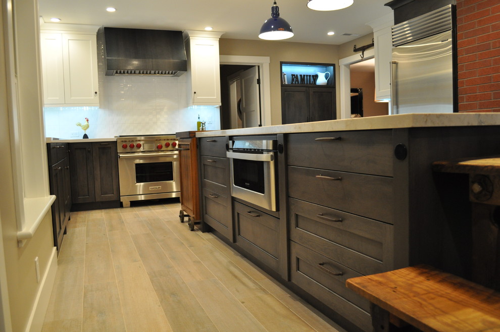 Photo of a large bohemian u-shaped kitchen/diner in Sacramento with a submerged sink, recessed-panel cabinets, grey cabinets, engineered stone countertops, white splashback, porcelain splashback, stainless steel appliances, porcelain flooring and an island.
