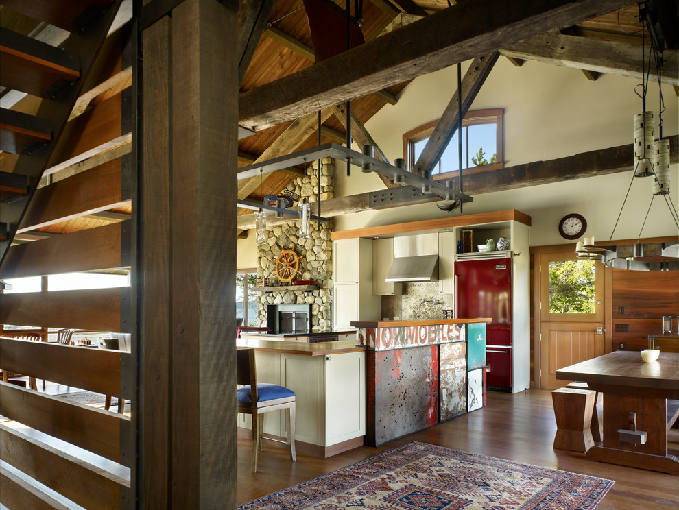 На фото: кухня-гостиная в стиле рустика с фасадами в стиле шейкер, бежевыми фасадами, деревянной столешницей и цветной техникой с