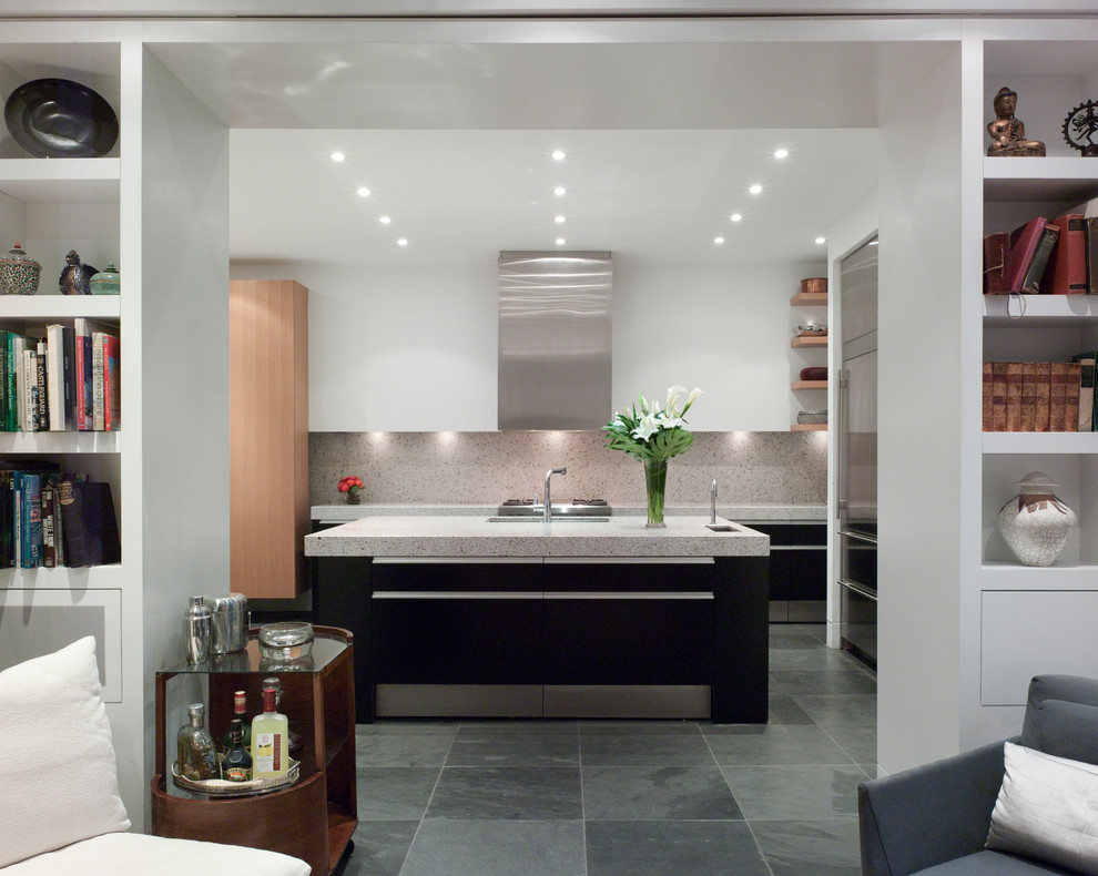 Cette image montre une cuisine design avec un placard à porte plane, des portes de placard noires, un électroménager en acier inoxydable et une crédence grise.