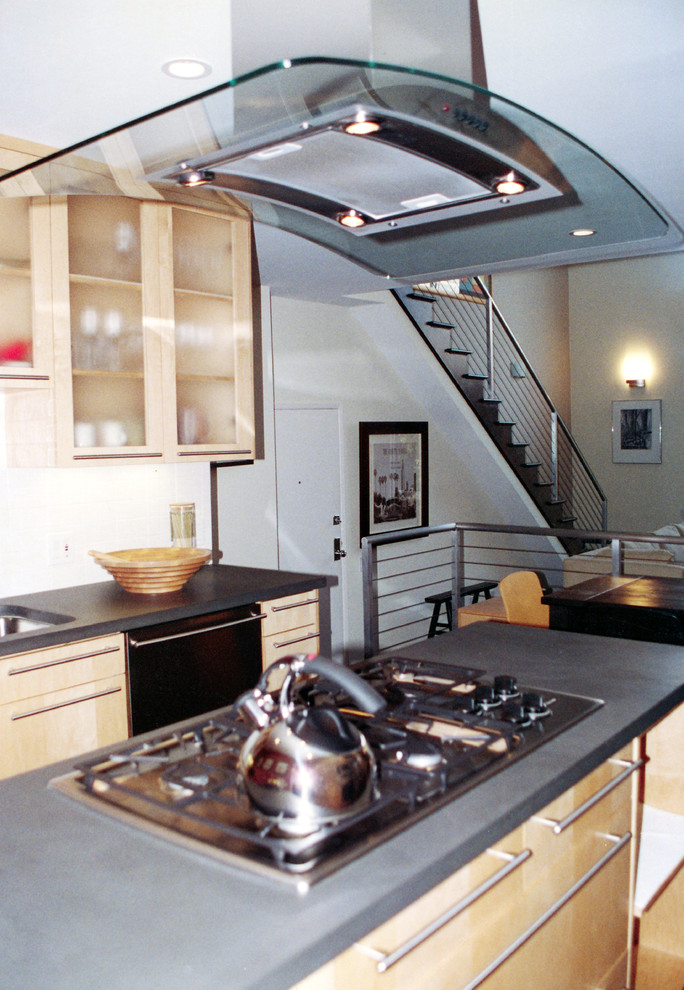 Cette image montre une cuisine américaine design en bois clair avec un placard à porte vitrée et îlot.