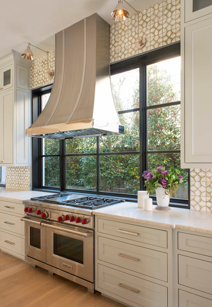 Photo of a large mediterranean kitchen in Dallas with recessed-panel cabinets, grey cabinets, quartz worktops, ceramic splashback, light hardwood flooring, beige floors, multi-coloured splashback and stainless steel appliances.