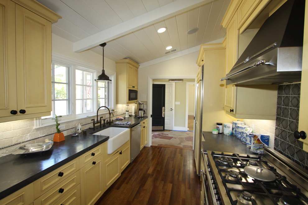 Diseño de cocina clásica cerrada con fregadero sobremueble, armarios con paneles empotrados, puertas de armario amarillas y electrodomésticos con paneles