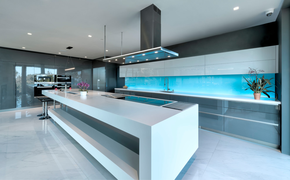 Immagine di un'ampia cucina design con lavello da incasso, paraspruzzi blu, pavimento bianco, top bianco, ante lisce, ante bianche, top in superficie solida, paraspruzzi con lastra di vetro e elettrodomestici in acciaio inossidabile