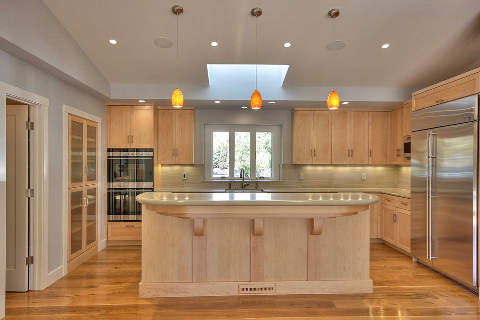 Exempel på ett stort modernt u-kök, med en enkel diskho, skåp i shakerstil, skåp i ljust trä, beige stänkskydd, rostfria vitvaror, mellanmörkt trägolv och en köksö