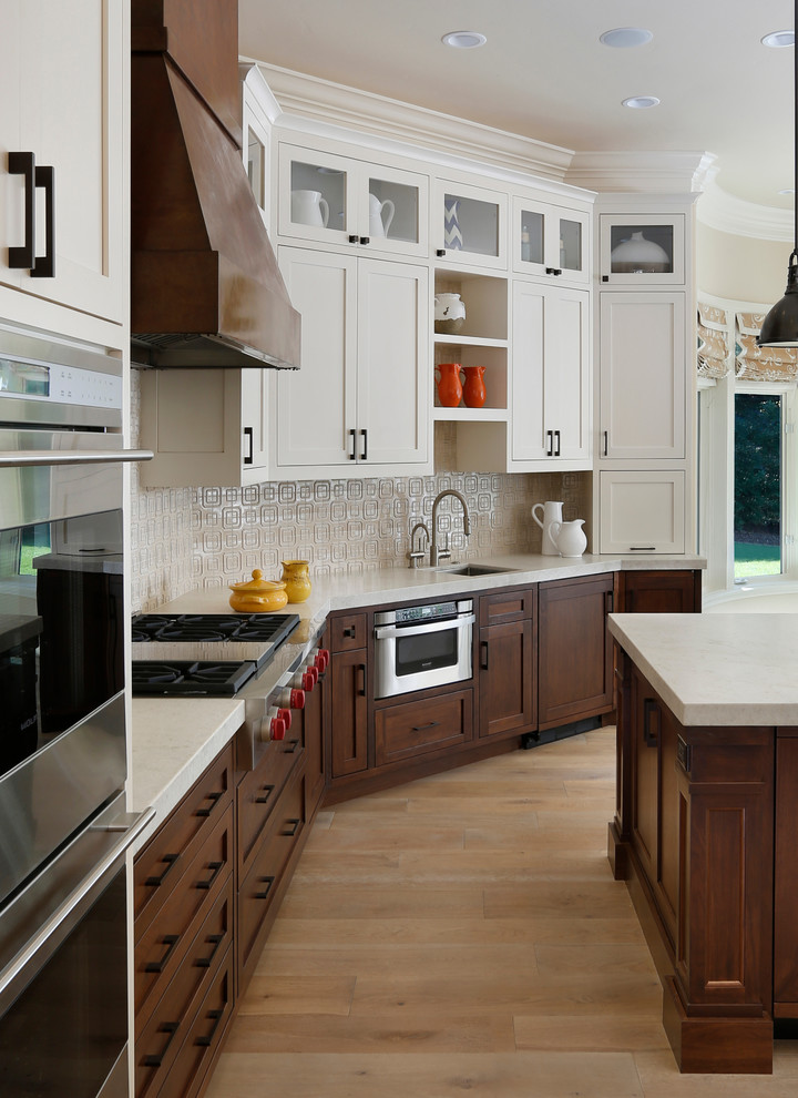 Diseño de cocina clásica renovada con fregadero bajoencimera, puertas de armario de madera en tonos medios, armarios con paneles empotrados, salpicadero blanco y electrodomésticos de acero inoxidable