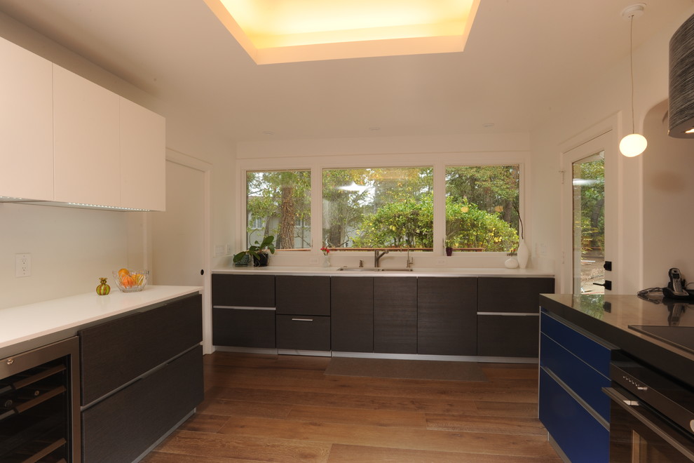 Bild på ett mellanstort funkis kök, med släta luckor, vita skåp, bänkskiva i koppar, rostfria vitvaror, mörkt trägolv och en köksö