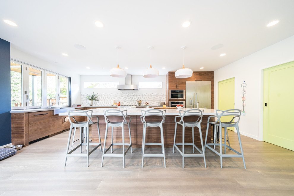 Kitchen - contemporary l-shaped light wood floor and beige floor kitchen idea in San Francisco with a farmhouse sink, flat-panel cabinets, medium tone wood cabinets, white backsplash, stainless steel appliances, an island and white countertops