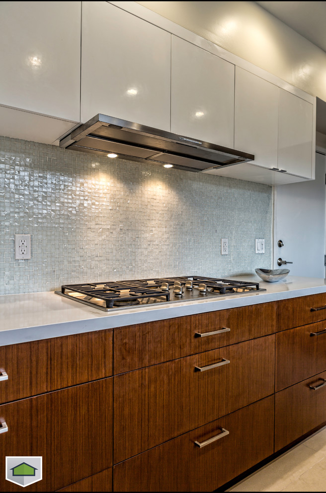 Cette image montre une cuisine américaine design en U avec un plan de travail en quartz modifié et un électroménager en acier inoxydable.