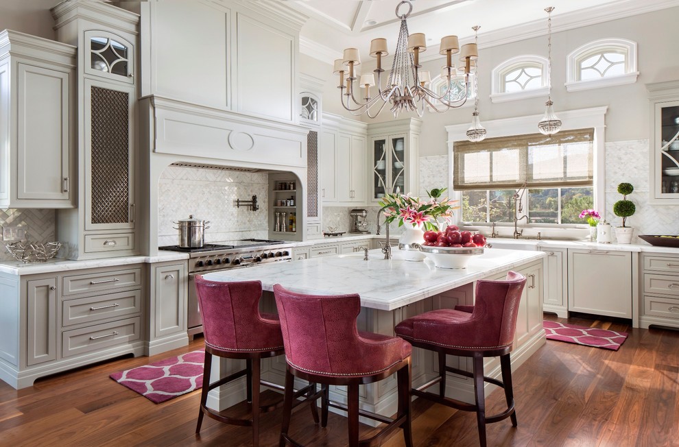Large traditional grey and pink l-shaped kitchen in San Francisco with a belfast sink, shaker cabinets, grey cabinets, marble worktops, white splashback, stainless steel appliances, medium hardwood flooring, an island and orange floors.