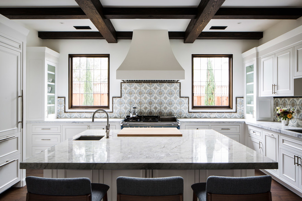 Foto på ett medelhavsstil grå u-kök, med en integrerad diskho, luckor med infälld panel, vita skåp, flerfärgad stänkskydd, stänkskydd i keramik, rostfria vitvaror, mörkt trägolv, en köksö och brunt golv