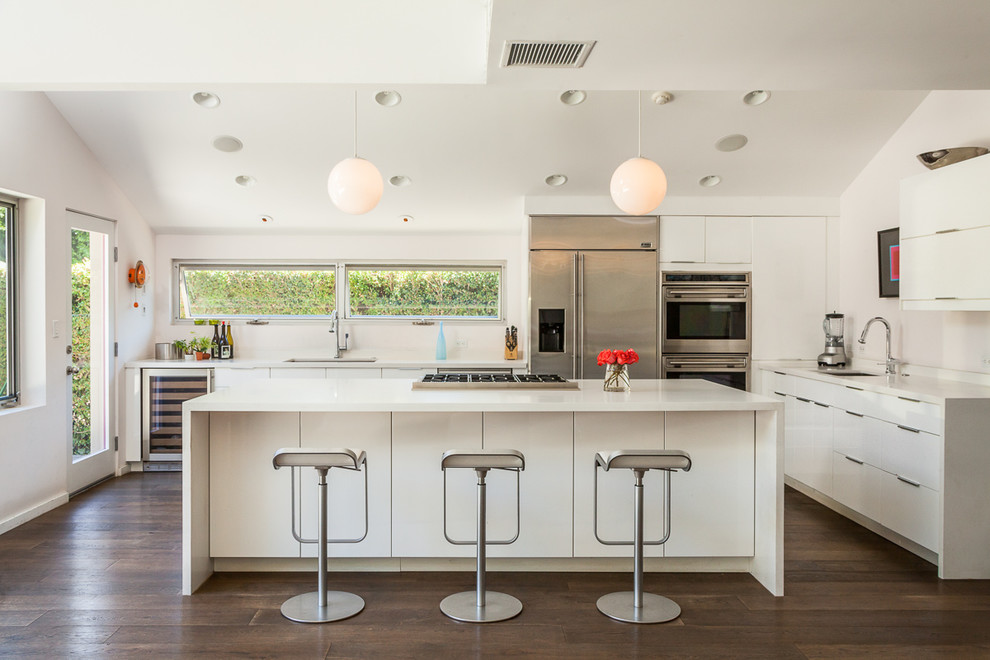 Mittelgroße Retro Küche in L-Form mit flächenbündigen Schrankfronten, weißen Schränken, Küchengeräten aus Edelstahl, dunklem Holzboden und Kücheninsel in Los Angeles