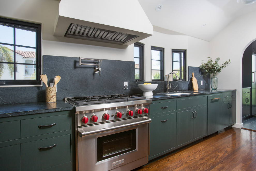 Foto på ett mellanstort medelhavsstil grön kök, med en undermonterad diskho, släta luckor, gröna skåp, träbänkskiva, grönt stänkskydd, rostfria vitvaror, mellanmörkt trägolv, en köksö och brunt golv