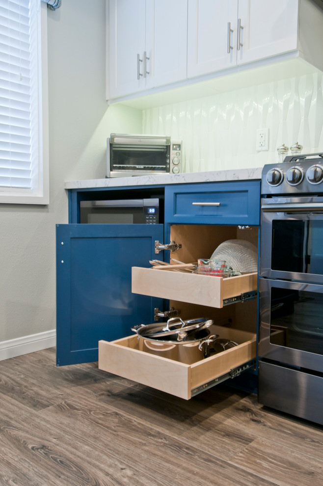 Exemple d'une petite cuisine moderne en L fermée avec un placard à porte plane, des portes de placard bleues, plan de travail en marbre, un électroménager en acier inoxydable, un sol en bois brun, îlot et un sol gris.