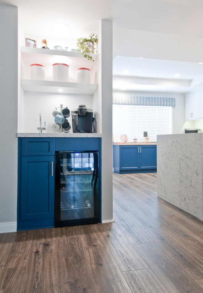 Inspiration pour une petite cuisine minimaliste en L fermée avec un placard à porte plane, des portes de placard bleues, plan de travail en marbre, un électroménager en acier inoxydable, un sol en bois brun, îlot et un sol gris.