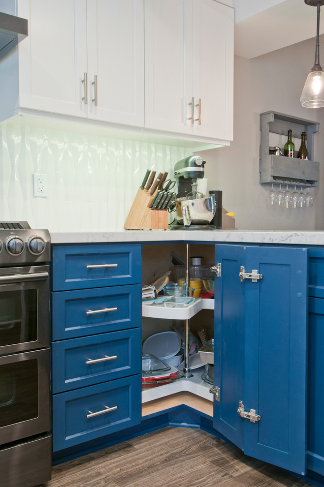 Bild på ett avskilt, litet funkis l-kök, med släta luckor, blå skåp, marmorbänkskiva, rostfria vitvaror, mellanmörkt trägolv, en köksö och grått golv