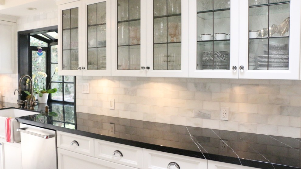 This is an example of a large traditional galley enclosed kitchen in Los Angeles with a belfast sink, beaded cabinets, white cabinets, composite countertops, grey splashback, stainless steel appliances and vinyl flooring.