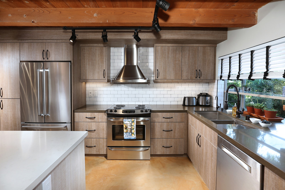 Medium sized industrial l-shaped open plan kitchen in Los Angeles with a triple-bowl sink, flat-panel cabinets, brown cabinets, composite countertops, white splashback, metro tiled splashback, stainless steel appliances, slate flooring and an island.