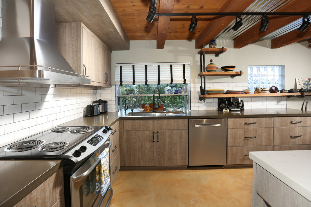 Photo of a medium sized urban l-shaped open plan kitchen in Los Angeles with a triple-bowl sink, flat-panel cabinets, brown cabinets, composite countertops, white splashback, metro tiled splashback, stainless steel appliances, slate flooring and an island.