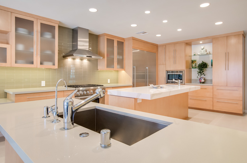 Inspiration for a large modern l-shaped ceramic tile eat-in kitchen remodel in Los Angeles with a farmhouse sink, flat-panel cabinets, light wood cabinets, quartz countertops, green backsplash, ceramic backsplash, stainless steel appliances and an island