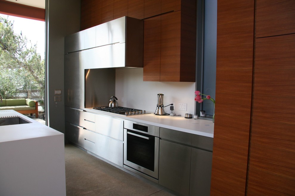 Photo of a modern kitchen/diner in Los Angeles with a submerged sink, white splashback, stainless steel appliances and an island.
