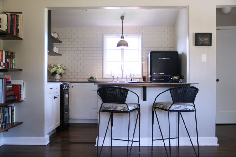 Klassische Küche in L-Form mit Schrankfronten mit vertiefter Füllung, weißen Schränken, Küchenrückwand in Weiß, Rückwand aus Metrofliesen und schwarzen Elektrogeräten in Los Angeles