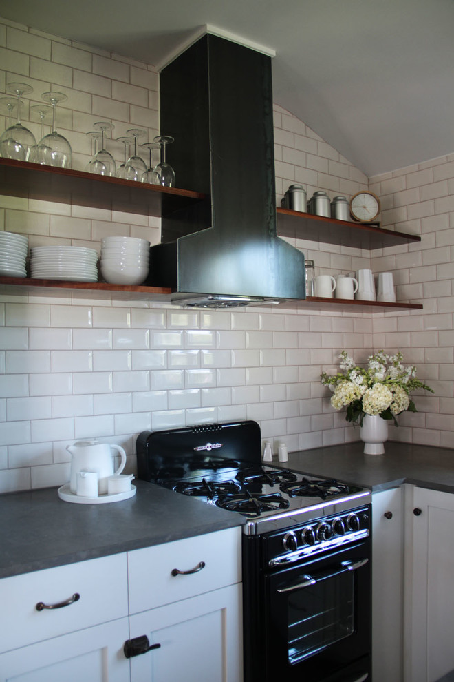 Example of a classic kitchen design in Los Angeles with open cabinets, black appliances, white backsplash, subway tile backsplash and limestone countertops