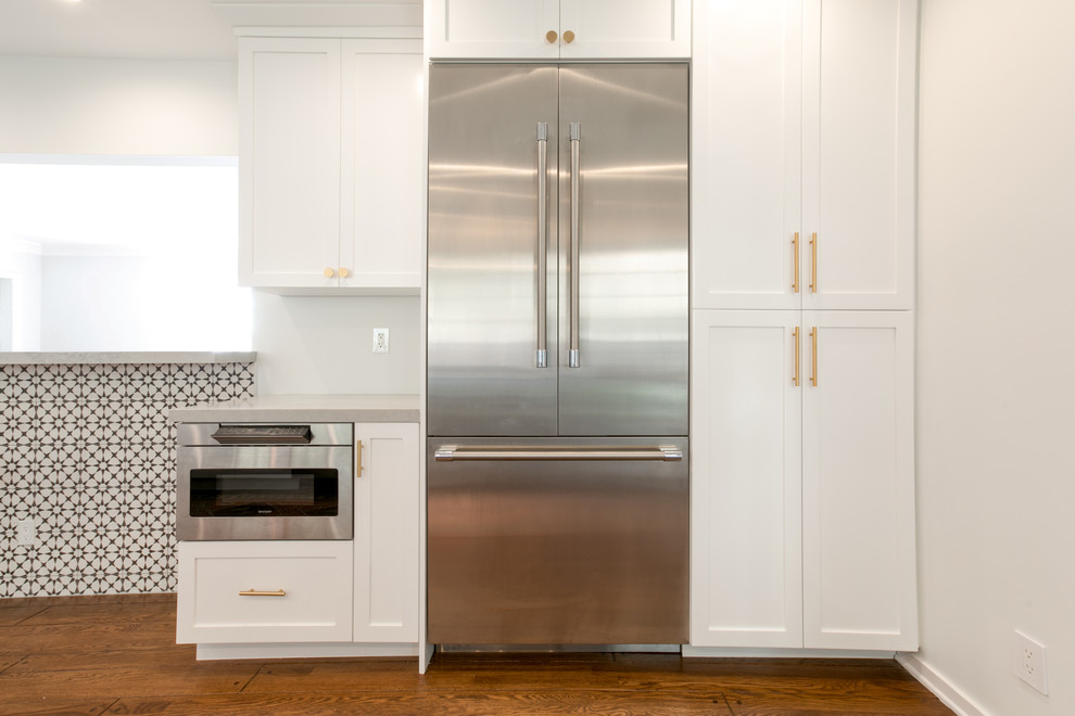 Bild på ett stort eklektiskt grå grått kök, med en nedsänkt diskho, skåp i shakerstil, vita skåp, bänkskiva i kvarts, vitt stänkskydd, stänkskydd i keramik, rostfria vitvaror, mellanmörkt trägolv och brunt golv