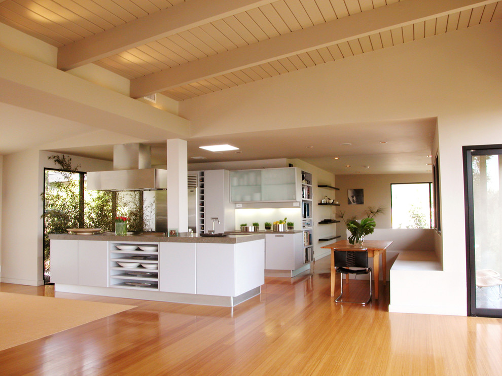 Exempel på ett modernt kök, med släta luckor, grå skåp, glaspanel som stänkskydd, rostfria vitvaror, bambugolv och en köksö