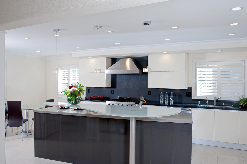 Exempel på ett modernt kök, med en undermonterad diskho, släta luckor, vita skåp, svart stänkskydd, rostfria vitvaror och bänkskiva i glas