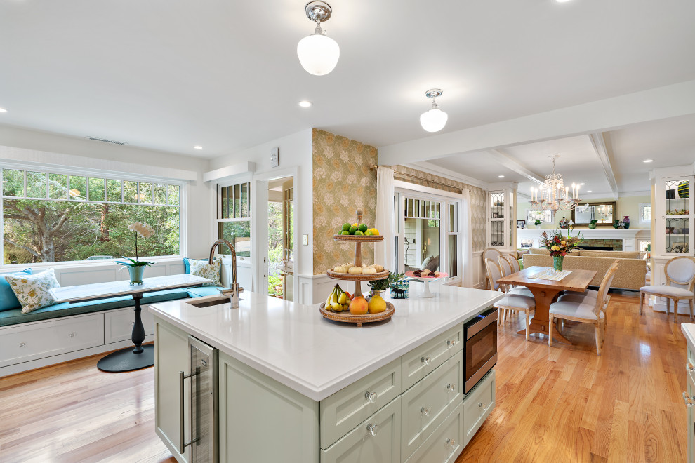 Photo of a medium sized classic kitchen/diner in San Francisco with a submerged sink, shaker cabinets, green cabinets, engineered stone countertops, white splashback, ceramic splashback, stainless steel appliances, medium hardwood flooring, an island, brown floors and white worktops.