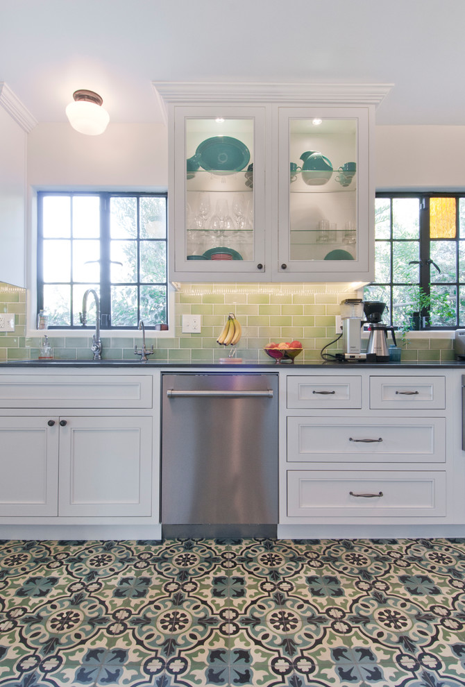 Inredning av ett eklektiskt avskilt, mellanstort grå grått l-kök, med en undermonterad diskho, luckor med infälld panel, vita skåp, bänkskiva i kvarts, grönt stänkskydd, stänkskydd i keramik, rostfria vitvaror, klinkergolv i porslin, en halv köksö och flerfärgat golv