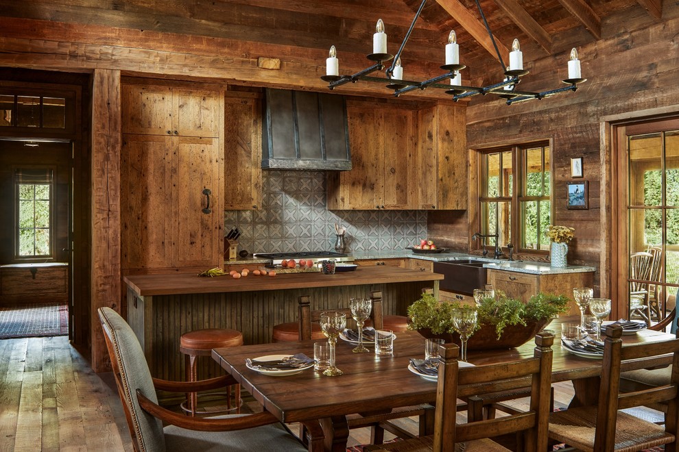 Idées déco pour une cuisine américaine montagne en L et bois brun avec un évier de ferme, une crédence grise, îlot, un plan de travail gris, parquet clair et fenêtre au-dessus de l'évier.