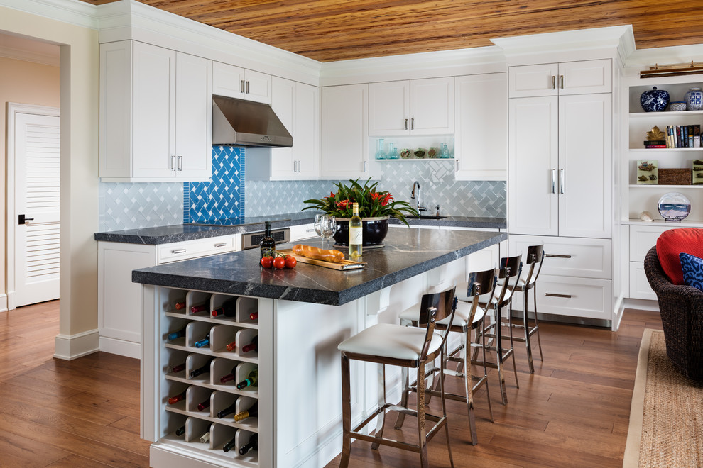 Bild på ett mellanstort maritimt kök, med en undermonterad diskho, vita skåp, marmorbänkskiva, grått stänkskydd, stänkskydd i keramik, rostfria vitvaror, mellanmörkt trägolv, en köksö, brunt golv och skåp i shakerstil