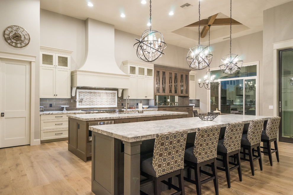Zweizeilige Klassische Küche mit Schrankfronten mit vertiefter Füllung, weißen Schränken, Küchenrückwand in Grau, hellem Holzboden, zwei Kücheninseln und braunem Boden in Phoenix