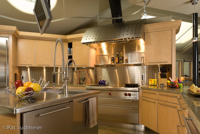 Inspiration för mellanstora moderna u-kök, med en integrerad diskho, släta luckor, skåp i ljust trä, granitbänkskiva, stänkskydd med metallisk yta, stänkskydd i metallkakel, rostfria vitvaror och en köksö