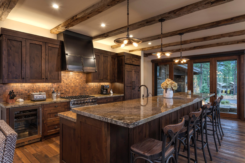 Cette image montre une cuisine américaine parallèle et encastrable chalet en bois foncé avec un placard à porte shaker, une crédence marron, une crédence en mosaïque, parquet foncé et îlot.