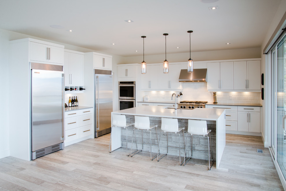 Inspiration for a large modern l-shaped kitchen/diner in Other with a belfast sink, shaker cabinets, white cabinets, engineered stone countertops, white splashback, ceramic splashback, stainless steel appliances, porcelain flooring, an island, grey floors and white worktops.