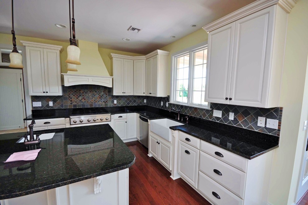 Exempel på ett stort klassiskt kök, med en rustik diskho, luckor med upphöjd panel, vita skåp, granitbänkskiva, grått stänkskydd, stänkskydd i keramik, rostfria vitvaror, mellanmörkt trägolv och en köksö