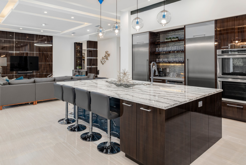 Moderne Küche mit Unterbauwaschbecken, flächenbündigen Schrankfronten, dunklen Holzschränken, Küchenrückwand in Grau, Küchengeräten aus Edelstahl, Kücheninsel und beigem Boden in Orlando