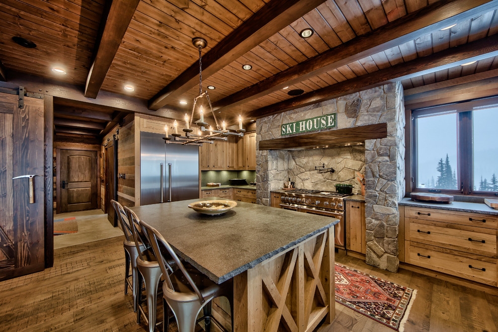 Exempel på ett stort rustikt l-kök, med luckor med infälld panel, skåp i ljust trä, bänkskiva i betong, rostfria vitvaror, en köksö, mellanmörkt trägolv och grönt stänkskydd
