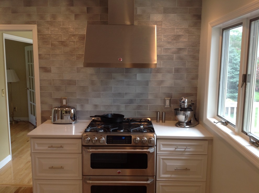 Photo of a medium sized classic l-shaped open plan kitchen in Boston with a submerged sink, raised-panel cabinets, white cabinets, marble worktops, grey splashback, stainless steel appliances, dark hardwood flooring and an island.