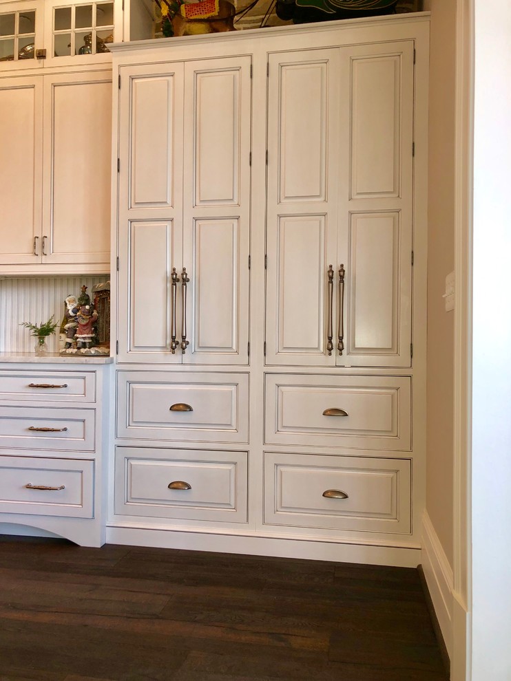 Cette photo montre une cuisine américaine nature avec un placard à porte affleurante, des portes de placard blanches, une crédence blanche, une crédence en céramique, parquet foncé, îlot et un sol marron.